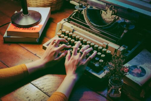 hands typing on an old typewriter on a wooden des