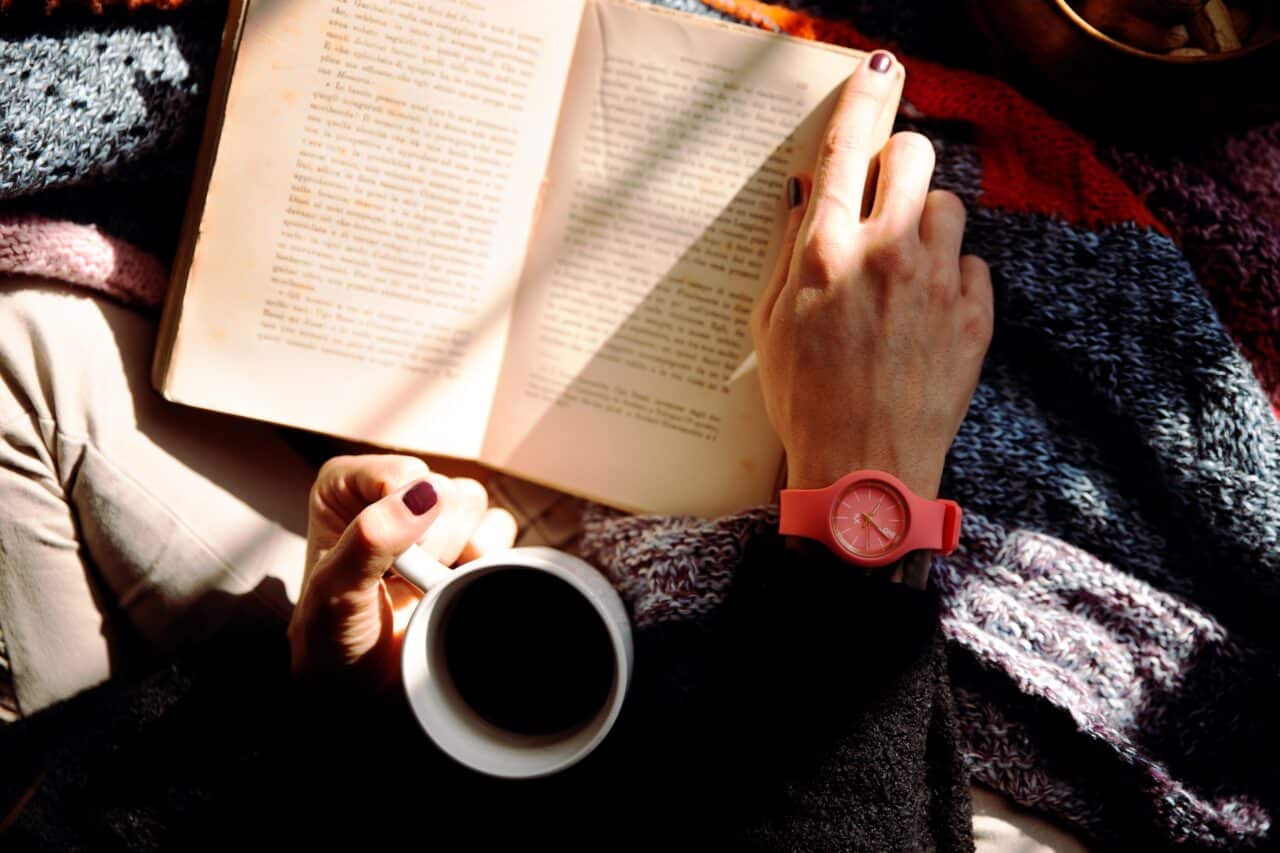 person reading a book and drinking coffee